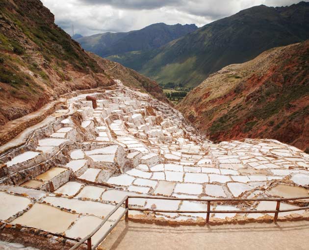 Maras Salt Mines in Peru showing thousands of white salt evaporation pools on a mountainside in the Sacred Valley near Cusco