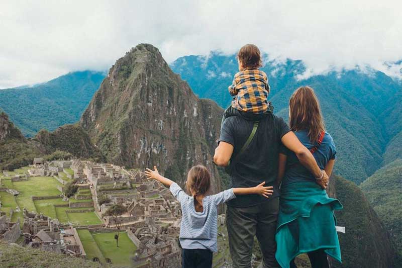Family with children looking out over Machu Picchu and Huayna Picchu, Peru