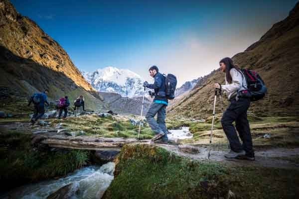 Group of tourists hiking along a mountain trail in the Andes, likely on the Salkantay Trek, surrounded by rugged peaks and high-altitude landscapes, Salkantay Trekking